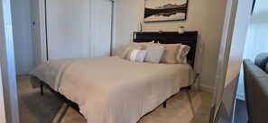 Ein Schlafzimmer mit einem Bett, einem Kopfteil, einem Wandbild und einer Tür.