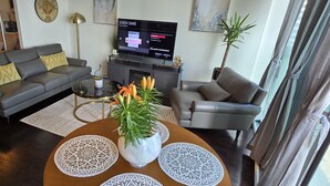 Un salon moderne comprenant un canapé, un fauteuil, une table basse et un téléviseur à écran plat.