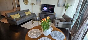 Ein modernes Wohnzimmer mit einer Couch, einem Sessel, einem Couchtisch und einem Flachbildfernseher.
