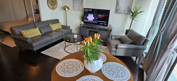 Een moderne woonkamer met een bank, fauteuil, salontafel en een flatscreen televisie.
