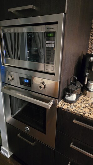 Eine Küche mit eingebautem Backofen und Mikrowelle, einer Kaffeemaschine und einer digitalen Uhr.