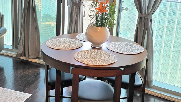 Un coin repas avec une table ronde, des chaises et un vase rempli de fleurs.