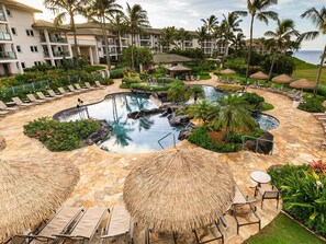 A resort pool area with lounge chairs, umbrellas, and a central water feature surrounded by greenery. - 2 Bedroom Villa at Marriott Kaua'i Lagoons (Lihue)