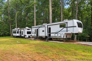 A row of RVs parked in a wooded area with a gravel path. - 12  bdrms/20 beds/pool/Hot Tub/3 RV`s/ATVs/30 acres (Ellenwood)