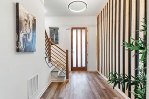 A hallway with a wooden staircase, a door with vertical blinds, and a wall-mounted air vent. - 12  bdrms/20 beds/pool/Hot Tub/3 RV`s/ATVs/30 acres (Ellenwood)
