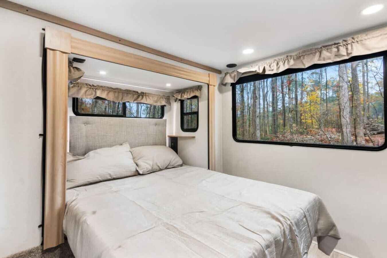 Une chambre à coucher avec un lit, une fenêtre donnant sur une forêt et une tête de lit.