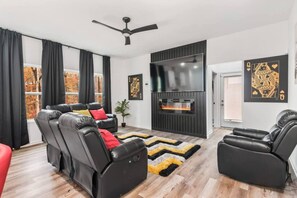 A modern living room with black leather sofas, a flat-screen TV, and a fireplace. - 12  bdrms/20 beds/pool/Hot Tub/3 RV`s/ATVs/30 acres (Ellenwood)
