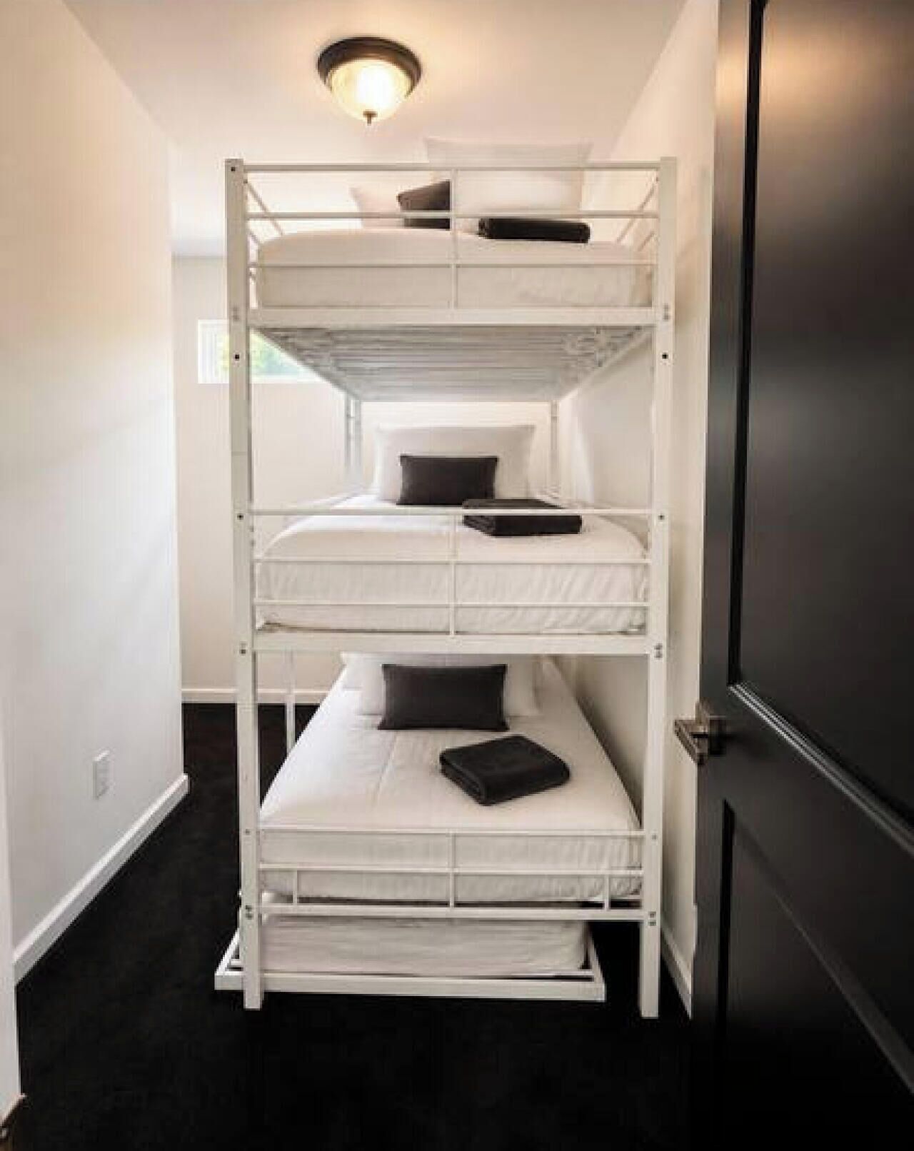 A bunk bed with three levels, each with a pillow and a blanket.