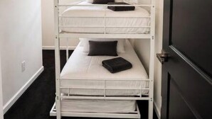 Ein Etagenbett mit drei Schlafstellen, jede mit Kissen und Decke.