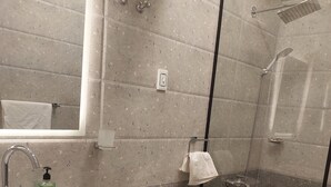 Een badkamer met een wastafel, toilet en glazen douchecabine.