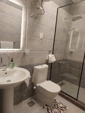 Ein Badezimmer mit Waschbecken, Toilette und Duschkabine aus Glas.