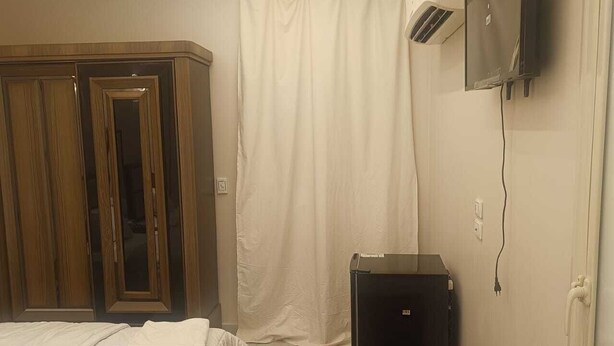 Een hotelkamer met een bed, een kledingkast, een televisietoestel en een airconditioner.