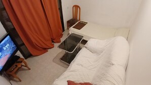 A small, single-bed room with a TV, a bedside table, and a chair. - Private Double Room with Air Conditioning, Exterior View (Toledo)
