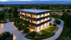 A modern multi-story house with a pool, surrounded by a landscaped garden and a view of distant mountains. - Lovely home in Zerava (Zerava)