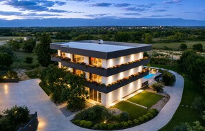 A modern multi-story house with a pool, surrounded by a landscaped garden and a view of distant mountains. - Lovely home in Zerava (Zerava)