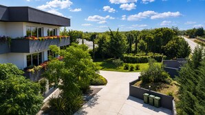 A modern building with a balcony, surrounded by lush greenery and a clear sky. - Lovely home in Zerava (Zerava)