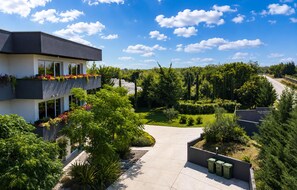 A modern building with a balcony, surrounded by lush greenery and a clear sky. - Lovely home in Zerava (Zerava)