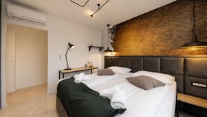 A modern bedroom with a bed, bedside tables, a desk, and a wall-mounted light fixture. - Lovely home in Zerava (Zerava)