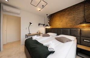 A modern bedroom with a bed, bedside tables, a desk, and a wall-mounted light fixture. - Lovely home in Zerava (Zerava)