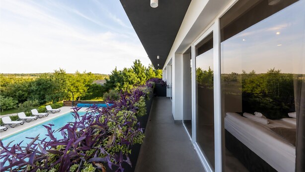 A balcony with a pool, lush greenery, and a clear view of the landscape. - Lovely home in Zerava (Zerava)
