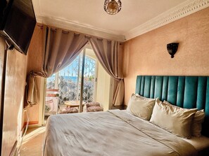 Ein Hotelzimmer mit Bett, Vorhängen, einem Fernseher und Blick auf die Stadt.