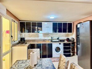 Eine kleine Küche mit Waschmaschine, Kühlschrank und Kaffeemaschine.