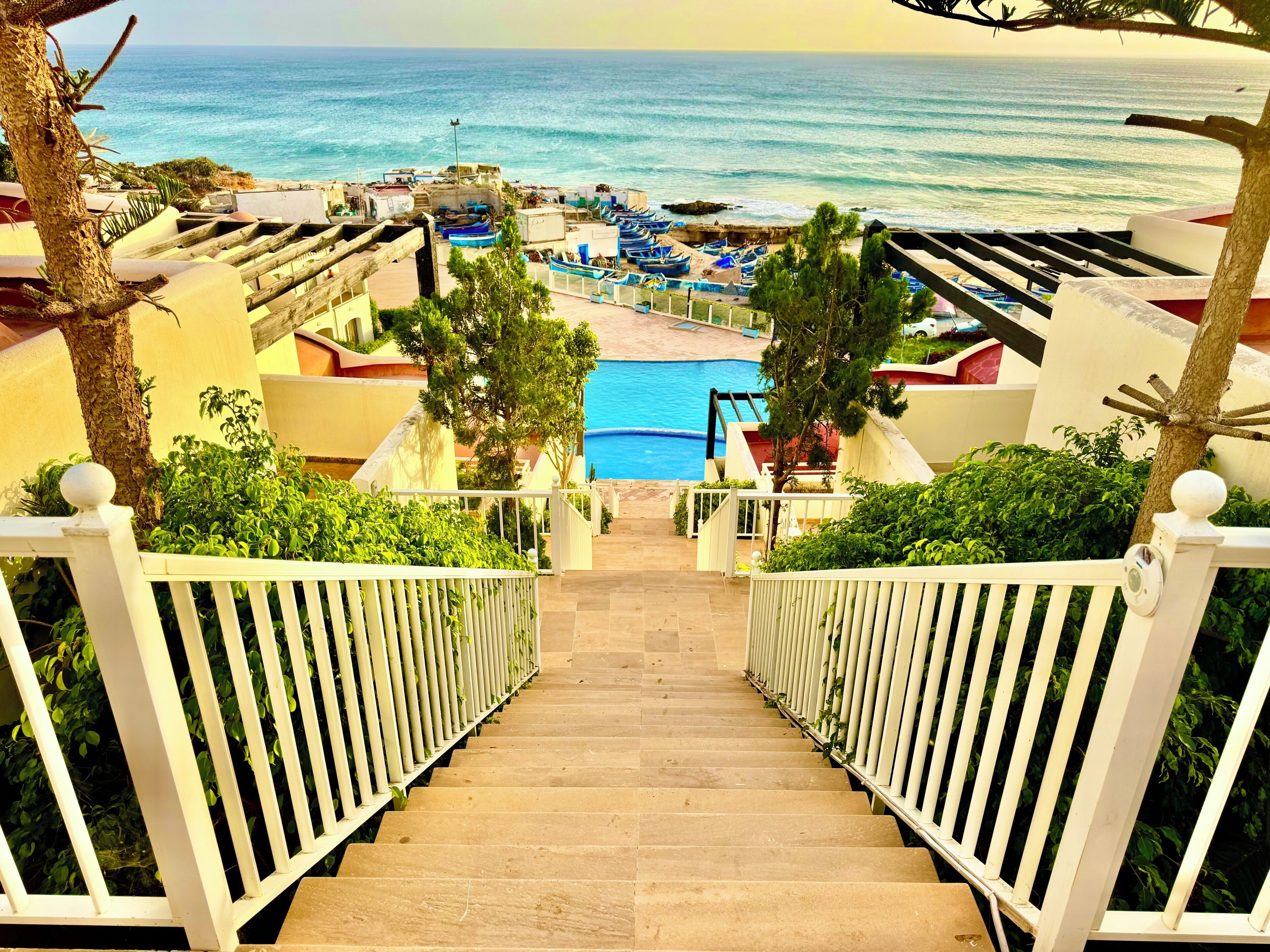 Gradi descensen cap a una piscina amb vistes al mar i a vaixells.