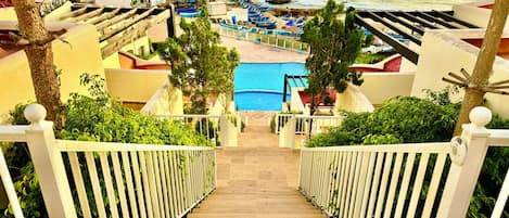 Una escalera que lleva a una piscina con vistas al mar y a barcos.