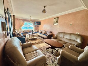 Ein Wohnzimmer mit einer Sofagarnitur, einem Couchtisch und einem Fernseher.