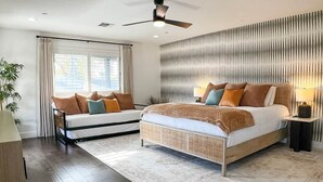 A bedroom with a bed, bedside tables, a ceiling fan, and a window with curtains. - Pool, Putts & Paradise | Modern Lux Golden Getaway (Scottsdale)