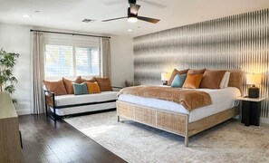 A bedroom with a bed, bedside tables, a ceiling fan, and a window with curtains. - Pool, Putts & Paradise | Modern Lux Golden Getaway (Scottsdale)