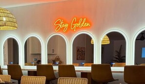 A room with a neon sign, mirrored wall, wicker chairs, and a table. - Pool, Putts & Paradise | Modern Lux Golden Getaway (Scottsdale)
