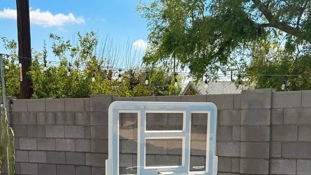 A poolside basketball hoop with a basketball on the ground. - Pool, Putts & Paradise | Modern Lux Golden Getaway (Scottsdale)