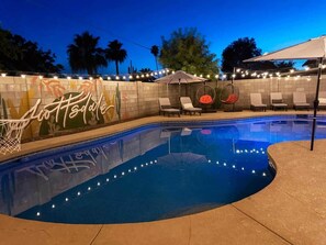 Una piscina con lettini e luci decorative.