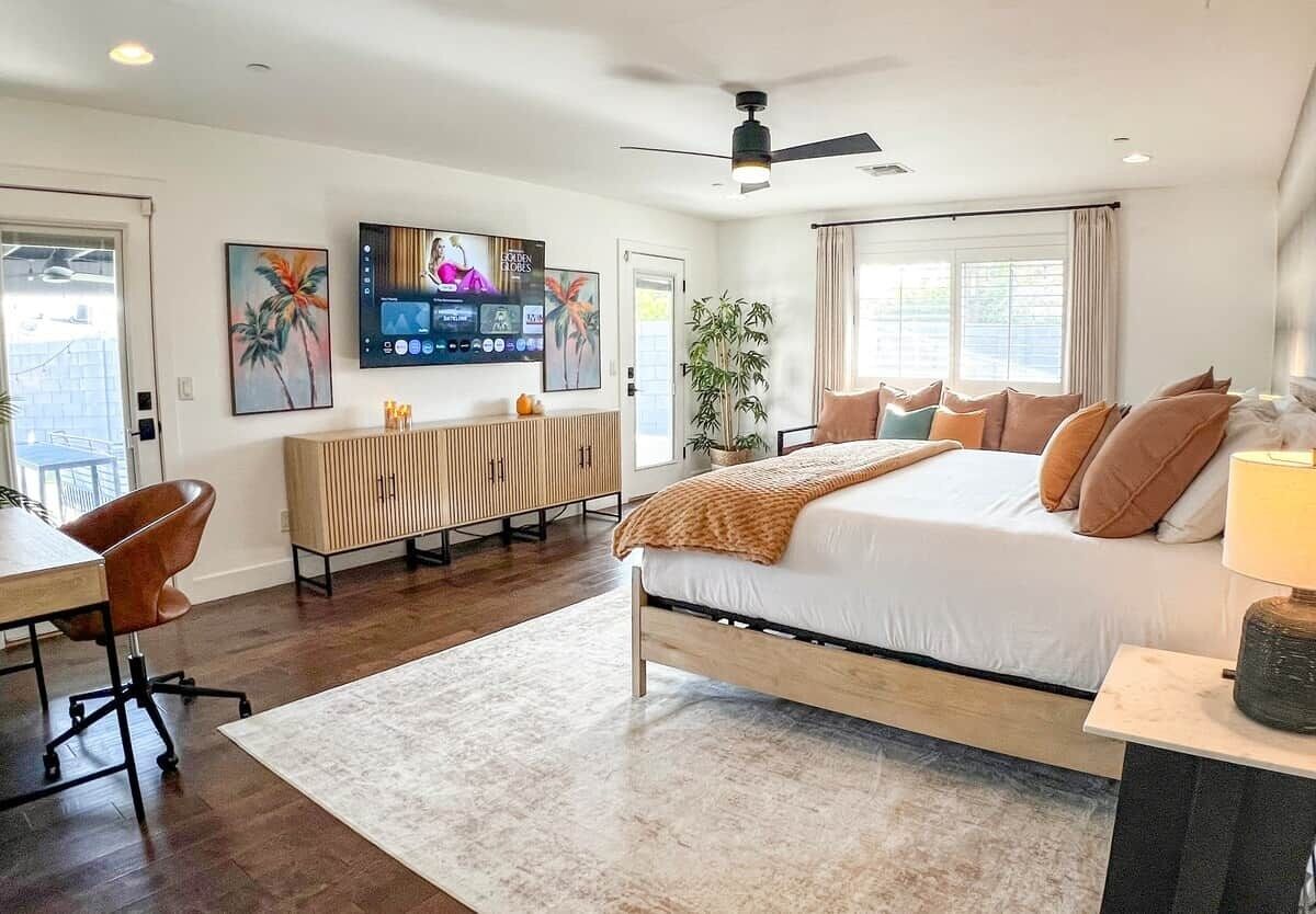 Un dormitorio con cama, escritorio, silla, televisión y ventilador de techo.