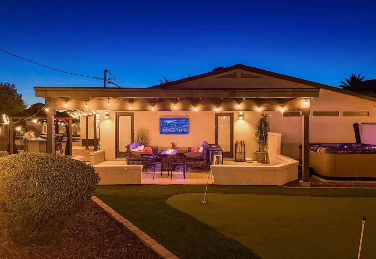 Propiedad residencial con una zona de estar cubierta al aire libre, un jacuzzi y un césped bien cuidado.