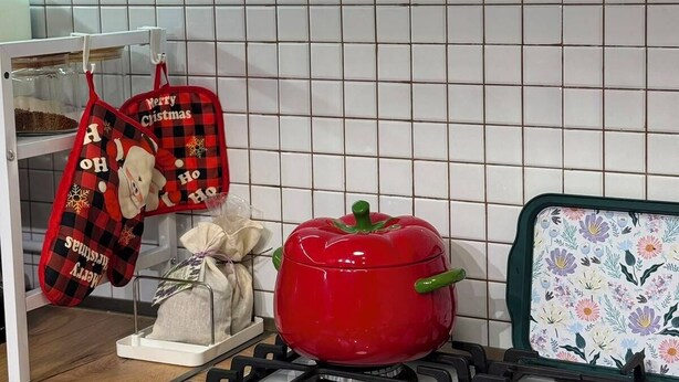 Een keuken met een gasfornuis, een rode pan en feestelijke keukendoeken.