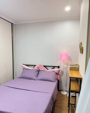 Ein Schlafzimmer mit einem Bett, einem Nachttisch, einer Lampe und einem Wandregal.
