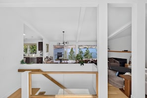 A modern interior with a staircase, a dining area, and a living room with a fireplace. - Lakefront Luxury on Okanagan Lake | Private Beach, Dock, Hot Tub & Sauna (Kelowna)