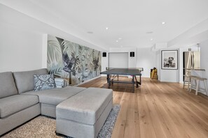 Ein modernes Wohnzimmer mit einem Ecksofa, einem Tischtennisschrank und einem großen, abstrakten Gemälde an der Wand.