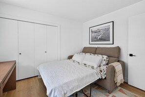 A bedroom with a bed, a sofa, a desk, and a wardrobe. - Lakefront Luxury on Okanagan Lake | Private Beach, Dock, Hot Tub & Sauna (Kelowna)