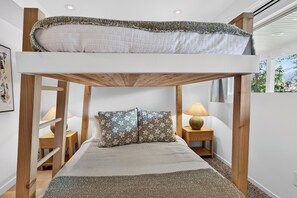 A bunk bed with a lofted sleeping area, two bedside tables with lamps, and a patterned rug on the floor. - Lakefront Luxury on Okanagan Lake | Private Beach, Dock, Hot Tub & Sauna (Kelowna)
