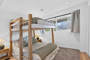 Ein Etagenbett mit Blick auf eine gebirgige Landschaft durch ein Fenster.