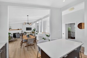 A modern interior with a dining area, kitchen, and living space. - Lakefront Luxury on Okanagan Lake | Private Beach, Dock, Hot Tub & Sauna (Kelowna)