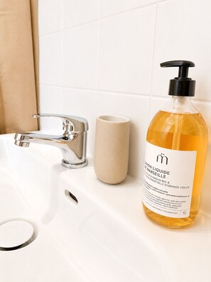 A bathroom sink with a chrome faucet and a beige cup. - Cozy Studio in the Heart of Nantes | Everything Within Walking Distance | Train Station 5 Minutes Away (Nantes)