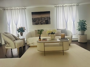 Ein Wohnzimmer mit einer Couch, einem Sessel, einem Couchtisch und einem Blumentopf.