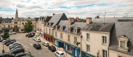 A street view with parked cars, buildings, and a church spire.