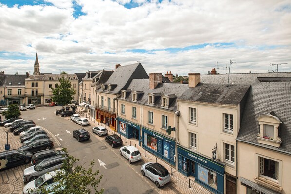 A street view with parked cars, buildings, and a church spire.
