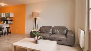 Ein modernes Wohnzimmer mit einem grauen Ledersofa, einem weißen Couchtisch und einer Lampe.