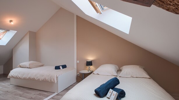 Ein Schlafzimmer mit zwei Betten, einem Oberlicht und einem kleinen Nachttisch mit Lampe.
